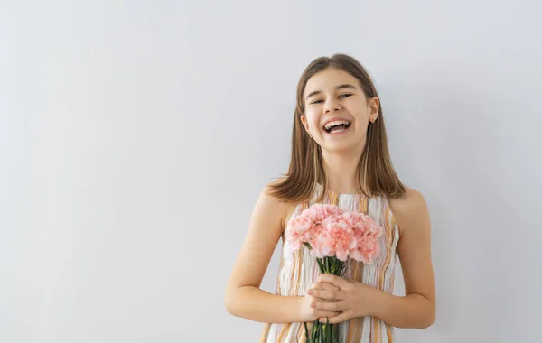 美丽的姑娘 双手捧着粉红的花朵 背靠着灰色的墙 — 图库照片