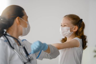 Doktor ve çocuk koronavirüs ve grip salgını sırasında maske takıyor. Virüs koruması. COVID-2019. Maske takıyor.