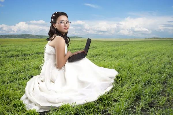 Menina sentada em uma grama com o computador — Fotografia de Stock