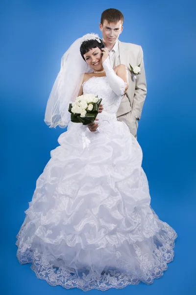 Loving groom and beautiful bride are happy together. Blue backgr — Stock Photo, Image