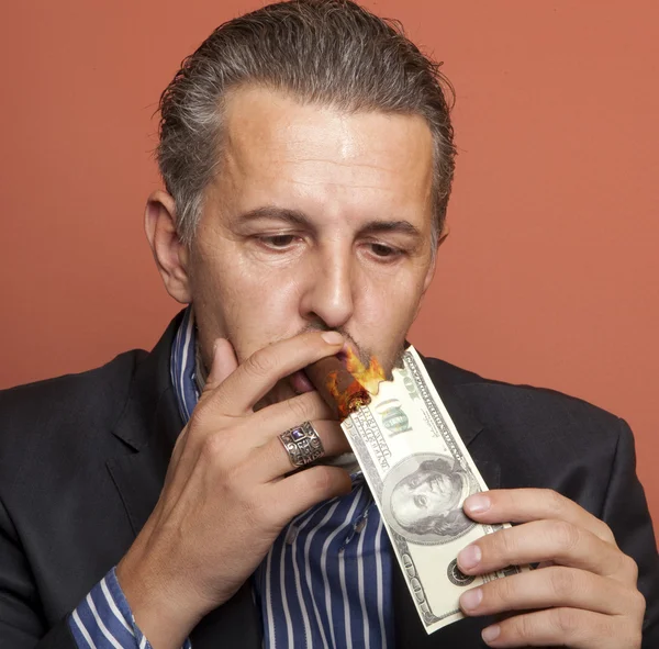 Un homme allume son cigare avec un billet de 100 dollars — Photo