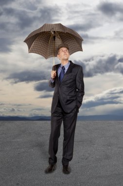 Businessman with umbrella under a stormy sky clipart