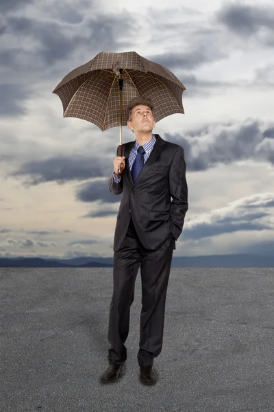 Homme d'affaires avec parapluie sous un ciel orageux — Photo