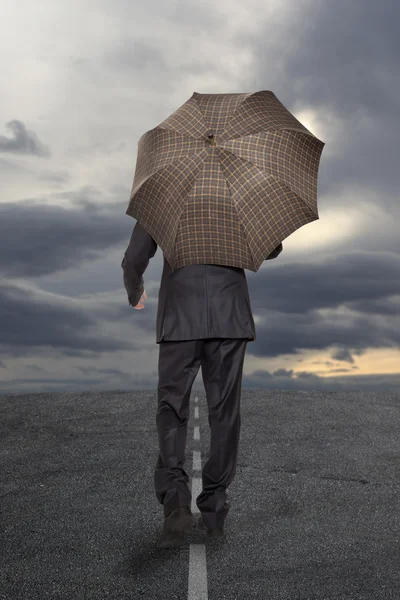 Geschäftsmann mit Regenschirm unter stürmischem Himmel — Stockfoto