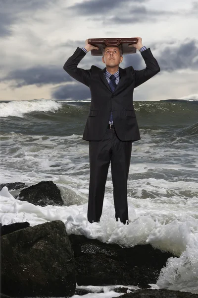 Young man using a briefcase as shelter with stormy sky in the ba — Stock Photo, Image