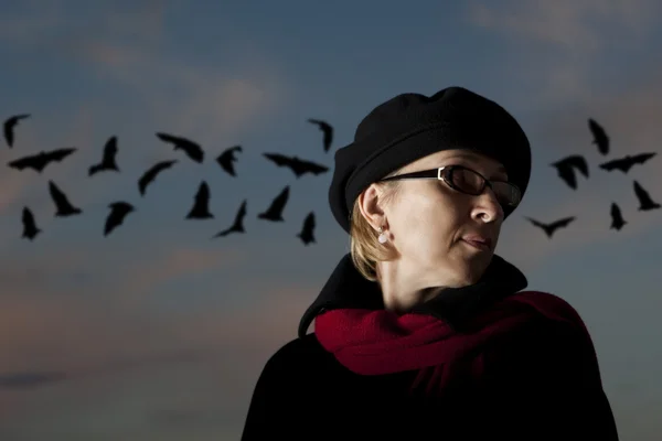 La mujer solitaria contra el cielo oscuro y los murciélagos —  Fotos de Stock