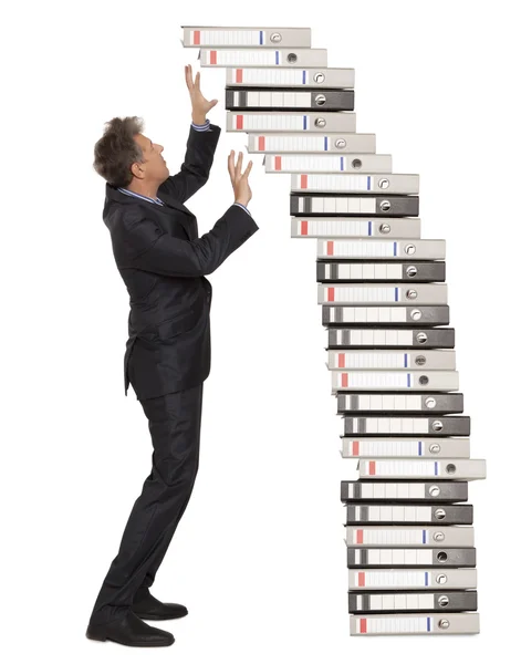 Hombre de negocios frustrado mirando un montón de carpetas de archivos —  Fotos de Stock