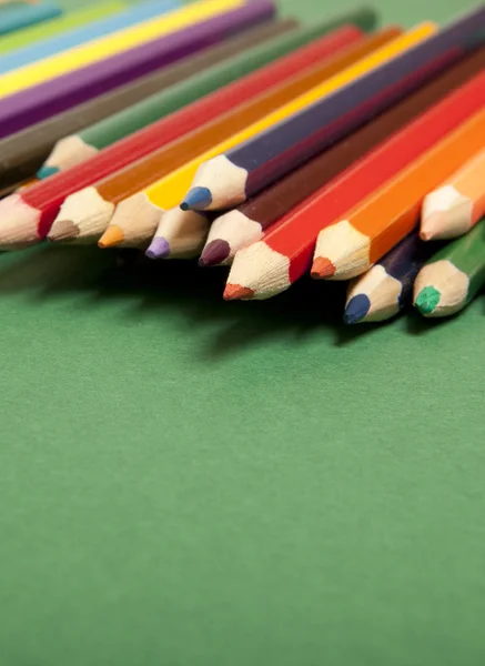 Yeşil arkaplanda renkli kalemler — Stok fotoğraf