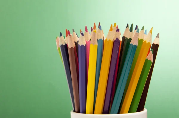 Yeşil arkaplanda renkli kalemler — Stok fotoğraf