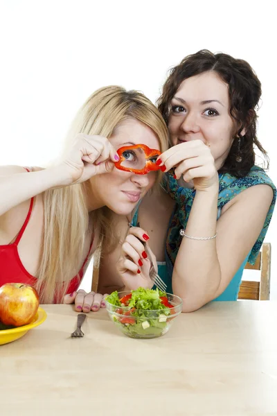 Girlfriends cheerfully play with meal behind a table — Stock Photo, Image