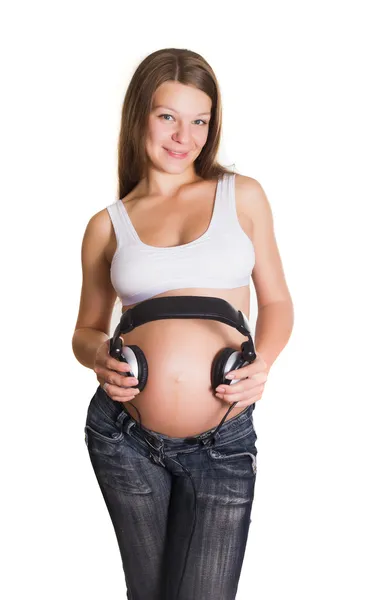 年轻孕妇的肚子上耳机 — 图库照片