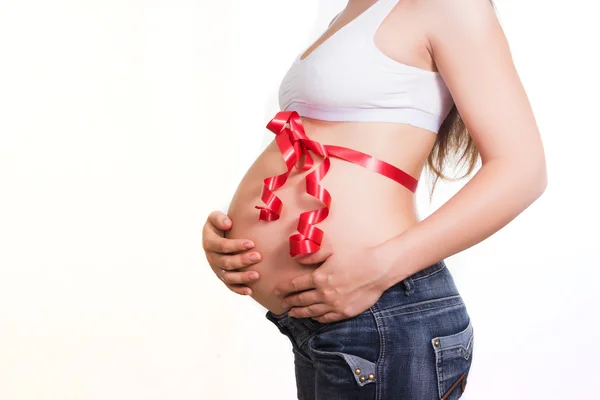 Pregnant tummy tied up by a red gift tape — Stock Photo, Image