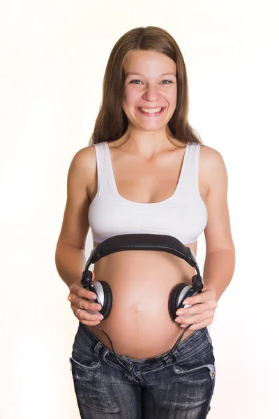 Giovane donna incinta con auricolari sulla pancia — Foto Stock