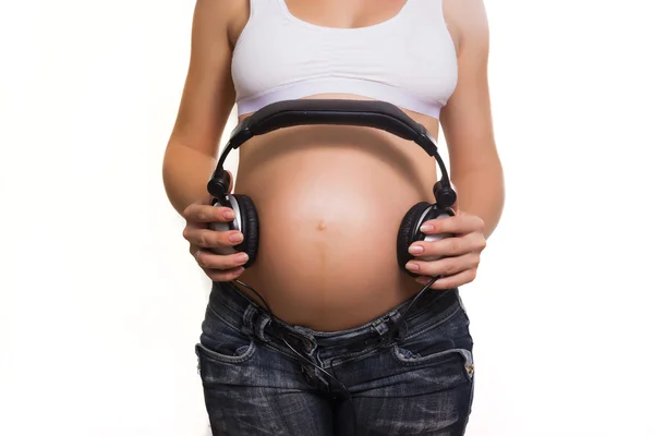 Young pregnant woman with earphones on the belly — Stock Photo, Image