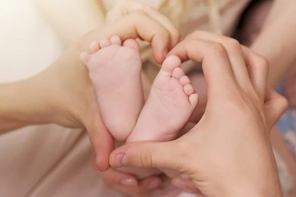 Close up of baby's heels and parent's hands — Stock Photo, Image