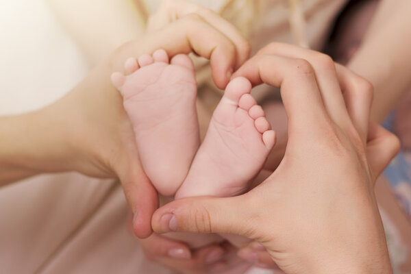 close up of baby 's heels and parent' s hands
