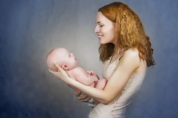 Mãe segura o bebê em mãos e fala com ele — Fotografia de Stock