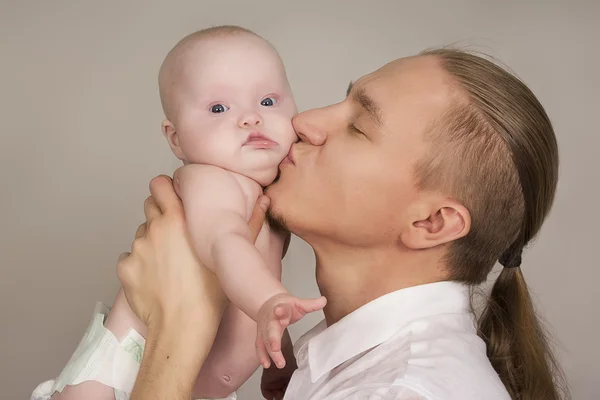 Fadern omfamnar det nyfödda barnet och leenden Royaltyfria Stockbilder