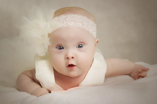 De baby in een jurk ligt op een kussen Stockfoto