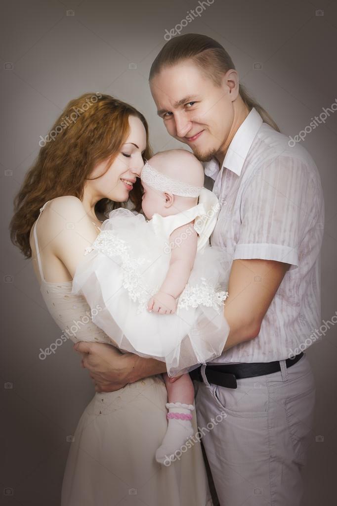 Naked mother and the father hold the kid on hands Stock Photo by
