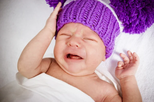 Crying baby in a violet knitted hat — Stock Photo, Image