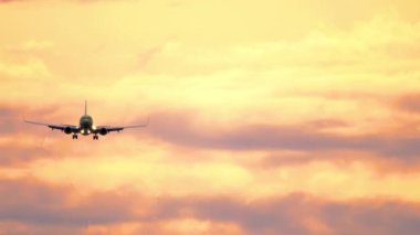 Gün batımında gökyüzünde bir uçak yaklaşıyor.