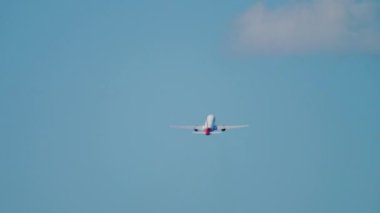 Rear view of a jet passenger plane gaining altitude after takeoff. Footage of a departing airliner in the blue sky. Unrecognizable plane flying away