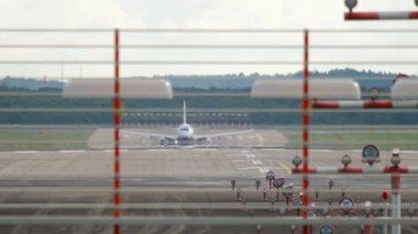 Civil airliner taking off, front view through airport signal lights. Unrecognizable plane flying away