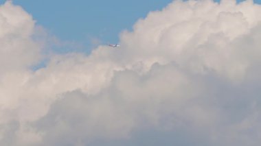 Passenger Airliner flies high in the clouds, view from below. Jet aircraft gaining altitude