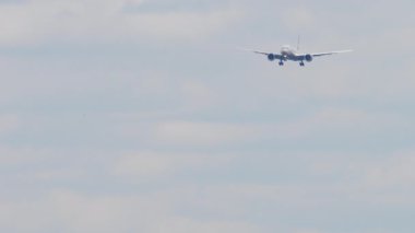 Slow shot, passenger jet plane approaching to land, front view. Aircraft with unrecognizable livery has released landing gear, flies