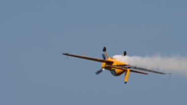 NOVOSIBIRSK, RUSSIAN FEDERATION - JULY 28, 2019: Yellow sports plane flies upside down, leaves smoke behind. Airshow at the Mochische aerodrome UNNM. Risky stunt in a plane at a Public Airshow