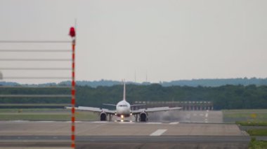 Passenger jet airplane braking after landing. Airliner arrival, view from the end of the runway. Tourism and travel concept.
