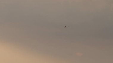 Long shot of airplane approaching to land in the sunset twilight sky