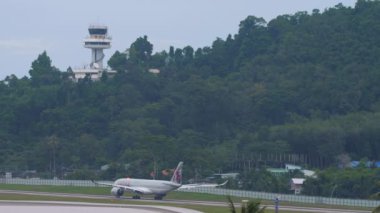 PHUKET, THAILAND - NOVEMBER 28, 2019: Passenger plane of Qatar Airways taxiing before departure from Phuket airport. View from the top floor of the hotel near airport. Tourism and travel concept, air