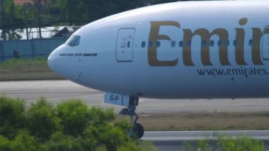 PHUKET, THAILAND - NOVEMBER 27, 2019: Emirates Boeing 777 passenger plane picks up speed on the runway at Phuket Airport. Footage of a passenger airliner picking up speed for takeoff. Tourism and