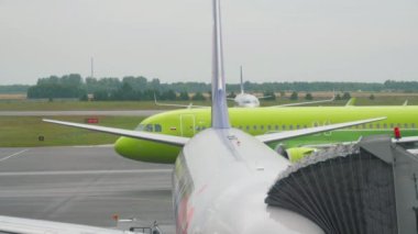 NOVOSIBIRSK, RUSSIAN FEDERATION - JULY 24, 2021: Passenger plane S7 Airlines taxiing on the runway at Tolmachevo airport. Airplane and telescopic bridge.