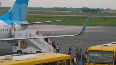 NOVOSIBIRSK, RUSSIAN FEDERATION - JULY 24, 2021: Passengers get off the plane Pobeda Airlines at Tolmachevo Airport. People ride the bus from the plane to the terminal