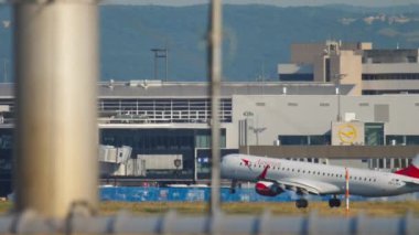 FRANKFURT AM MAIN, GERMANY - JULY 19, 2017: Long shot of passenger airplane Embraer Austrian Airlines landing at Frankfurt international airport. Slow motion, narrow body aircraft flying