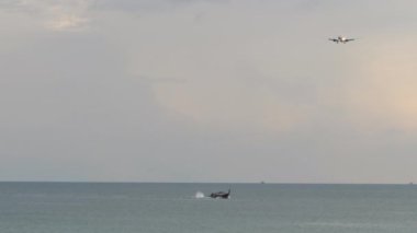 Airplane approaching to land. Plane descending over the ocean in cloudy weather. Tourism and travel concept