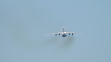 Transport heavy aircraft climb after takeoff, long shot rear view. Multipurpose fixed-wing four-engine turbofan strategic aircraft