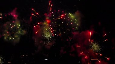 Slow-motion footage of bright multicolored festive fireworks with golden sparks in the black night sky