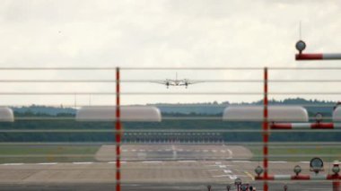 An unidentified turboprop aircraft descends to land at an airport in Europe. Front view through the landing lights on the runway