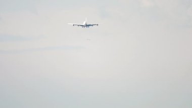 Wide-body unrecognizable aircraft approaching landing, front view on a long shot. Tourism and aviation concept