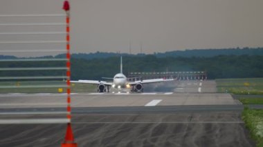 Civil aircraft opened flaps and braking after landing at european airport. View from the end of the runway