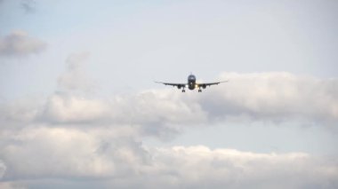 Bottom view, silhouette of a passenger jet aircraft approaching for landing against a cloudy gray sky. Tourism and aviation concept
