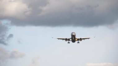 Passenger jet aircraft approaching for landing against a cloudy gray sky. Tourism and aviation concept