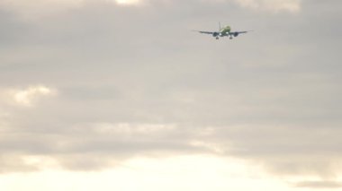 Super slow motion, long shot of an airplane approaching to land in a cloudy sky