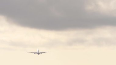 Airplane flies away, silhouette in the sky. Long shot, airliner climb after takeoff