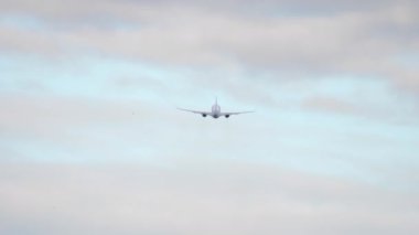 Civil jet airplane departure and climb, long shot rear view. Commercial aircraft flying away. Tourism and travel concept