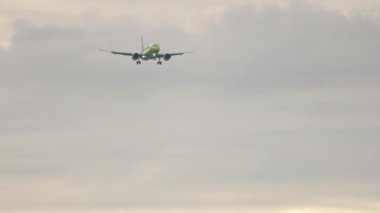 Slow motion, jet airplane approaching to land in a cloudy sky. Tourism and travel concept